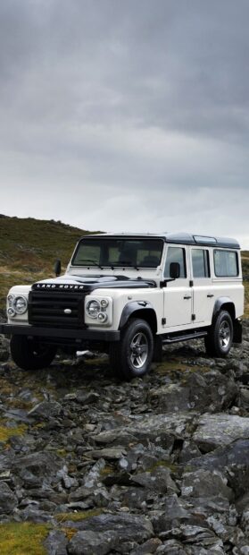 The Land Rover Defender is parked on rocky terrain under cloudy skies, HD Phone Wallpaper