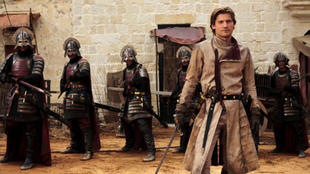A Lannister soldier stands with his armed guards in a medieval courtyard, HD Desktop Wallpaper