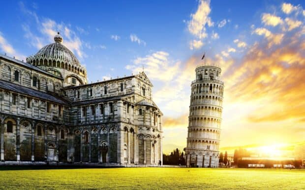 The Tower of Pisa stands beside the historic building under a vibrant sunset sky, 2K Desktop Wallpaper
