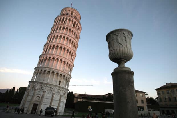 The leaning Tower of Pisa stands beside a carved stone urn during dusk, HD Desktop Wallpaper