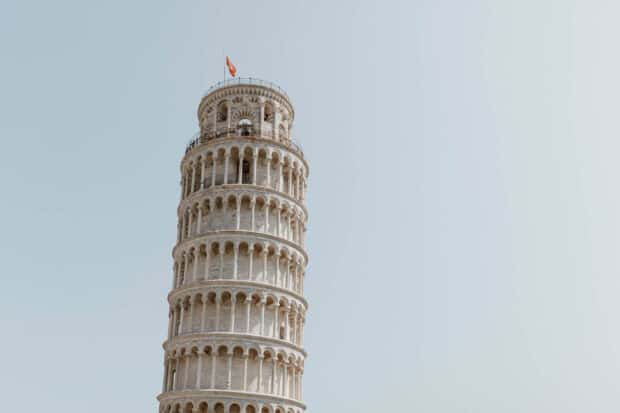 The Leaning Tower of Pisa stands prominently against a clear sky with a flag on top, HD Desktop Wallpaper