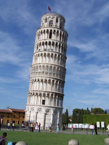 The Leaning Tower of Pisa stands with visitors on the grass nearby during a sunny day, 2K Mobile Wallpaper