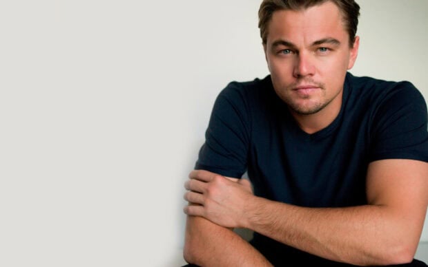 A close up portrait of Leonardo Dicaprio wearing a black shirt and looking at the camera, 2K Desktop Wallpaper