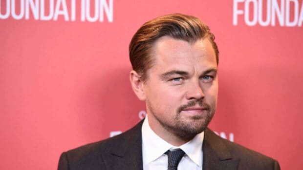 Leonardo Dicaprio in a black suit and tie posing with a red background, 4K Desktop Wallpaper