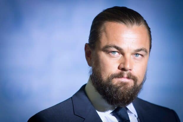 Leonardo Dicaprio is wearing a dark suit and tie with a full beard and blue eyes in this portrait, HD Desktop Wallpaper
