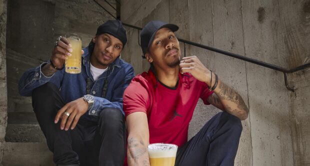 The Les Twins are sitting on concrete stairs enjoying drinks and relaxing in casual clothes, 2K Desktop Wallpaper