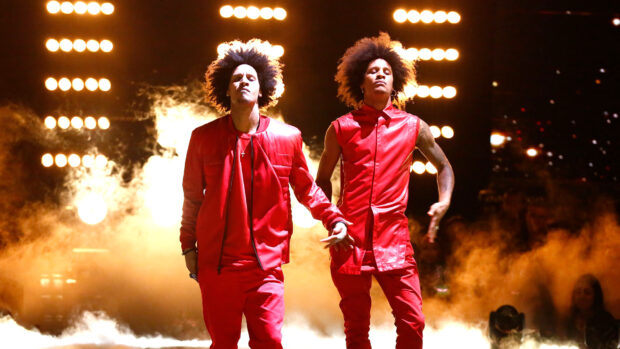Les Twins perform a dance routine wearing red outfits with bright stage lights behind them, HD Desktop Wallpaper
