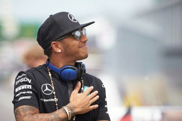 Lewis Hamilton smiles wearing a black cap and headphones on his neck, 2K Desktop Wallpaper