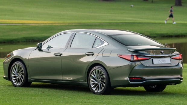 The Lexus ES hybrid luxury sedan is parked on a grassy field near a golfer, HD Desktop Wallpaper