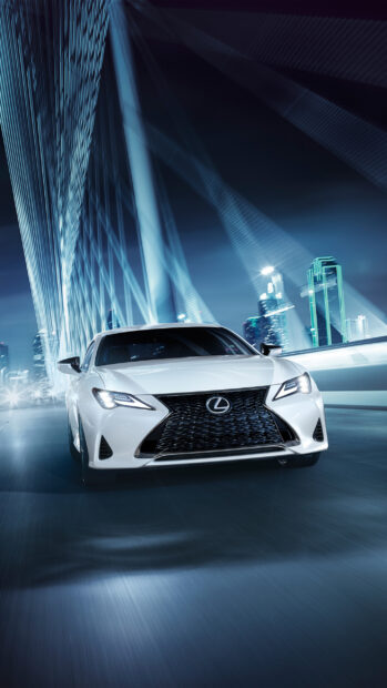 A white Lexus Es driving quickly on a city bridge at night with skyscrapers in the background, 2K Phone Wallpaper