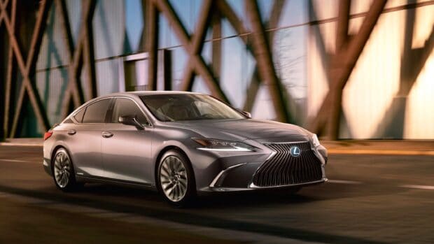 A silver Lexus Es sedan driving past a modern building with glass windows, 2K Desktop Wallpaper