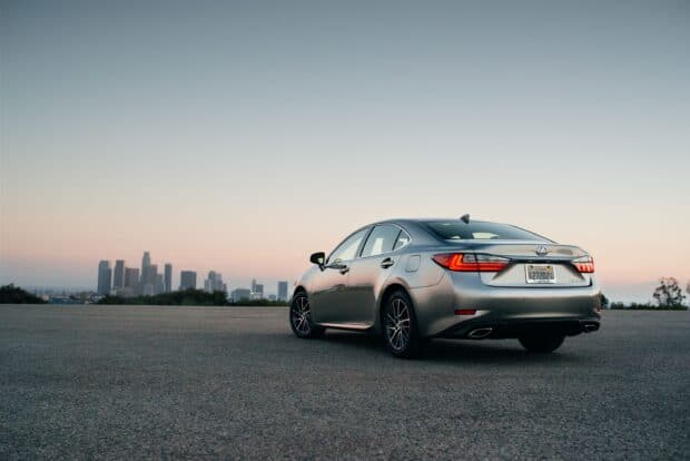 A silver Lexus Es car is parked with city skyline in the distant background at sunset, 2K Desktop Wallpaper