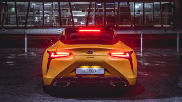 The Lexus LC 500 is shown from the rear with illuminated red tail lights in a dark setting, 2K Desktop Wallpaper