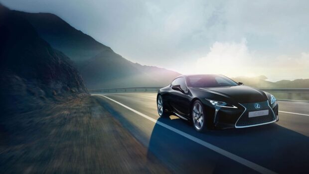 A black Lexus LC 500h is driving fast on a curved mountain road at sunrise, HD Desktop Wallpaper