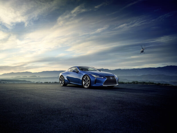 A blue Lexus LC is parked on a road with mountains and clouds in the background, 2K Desktop Wallpaper