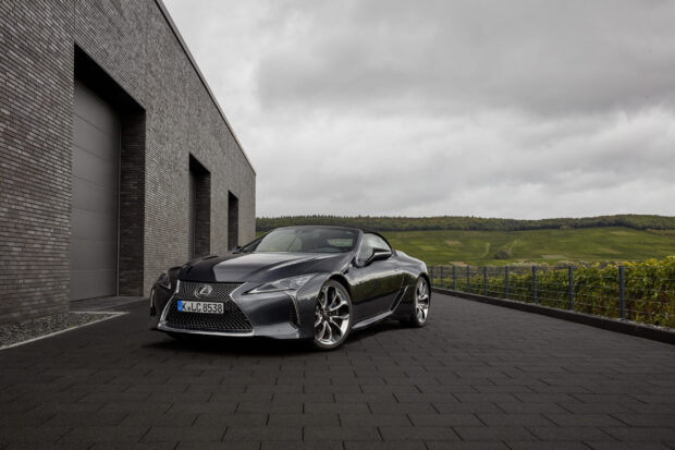 A Lexus LC sports car is parked on a paved surface near a modern building under cloudy skies, 2K Desktop Wallpaper