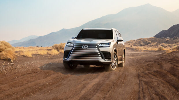 A Lexus LX driving on a dusty desert road with mountains in the background, HD Desktop Wallpaper