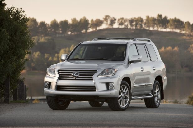 A silver Lexus LX is parked on a quiet road near a lake with trees in the background, 2K Desktop Wallpaper