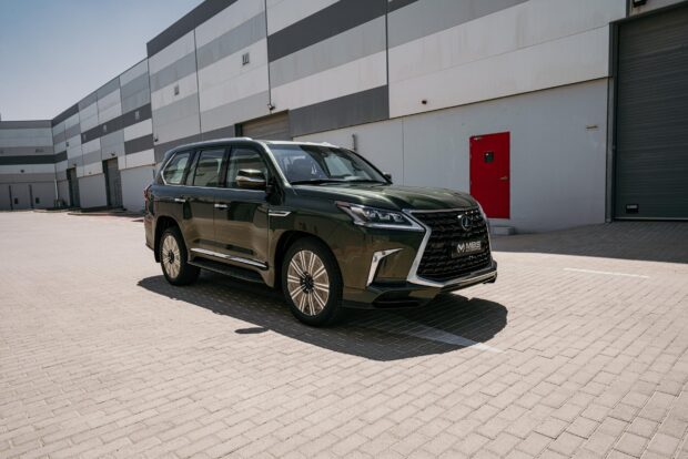 A black Lexus LX is parked outside a commercial building under clear daylight, HD Desktop Wallpaper