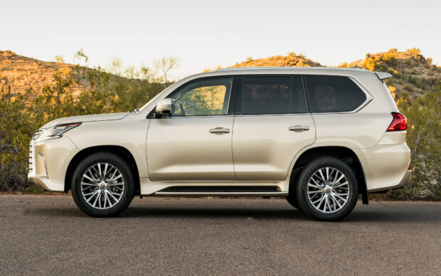 A beige Lexus LX SUV is parked on a desert road near shrubs and hills, HD Desktop Wallpaper
