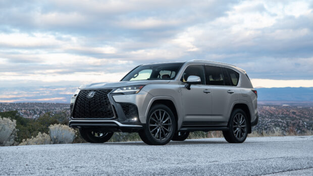 A silver Lexus LX SUV is parked on a road with mountains and cloudy sky in the background, 4K Desktop Wallpaper