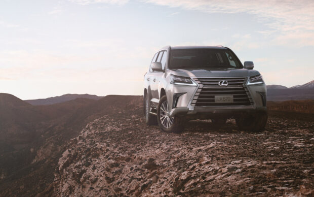 A Lexus LX570 is parked on rugged rocky terrain with mountains in the background at sunset, HD Desktop Wallpaper