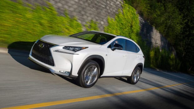 A white Lexus Nx is shown driving quickly on a paved road with greenery and a stone wall in the background, 4K Desktop Wallpaper