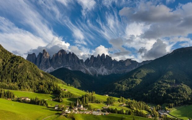A beautiful view of Liechtenstein with green hills and striking mountain peaks under a cloudy sky, HD Desktop Wallpaper