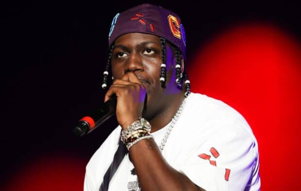 Lil Yachty is holding a microphone during a concert with red lighting in the background, HD Desktop Wallpaper