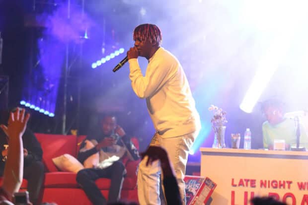 Lil Yachty is singing into a microphone during a live show with bright stage lights, HD Desktop Wallpaper