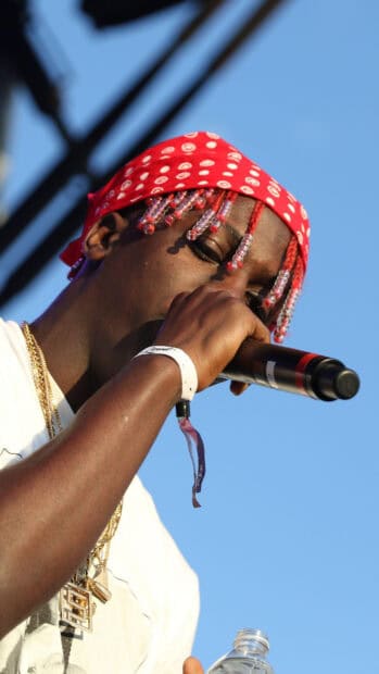 Lil Yachty wearing a red bandana and holding a microphone while performing outdoors, 2K Phone Wallpaper