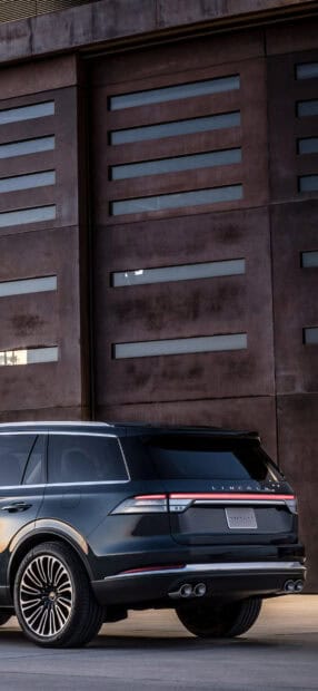 A Lincoln Aviator is parked near a modern building with horizontal windows, HD Phone Wallpaper