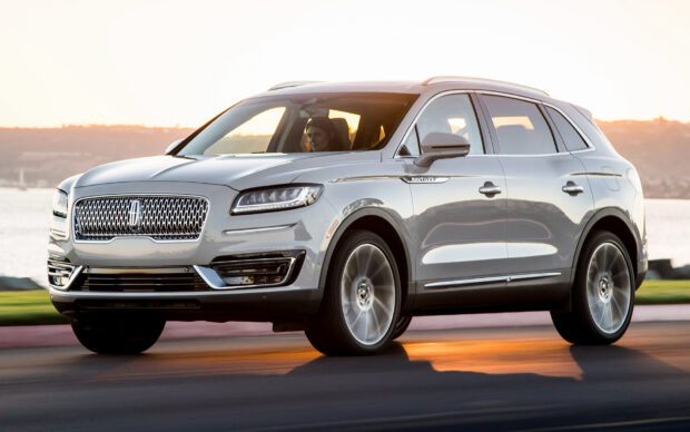 A silver Lincoln Nautilus drives along a road by the water at sunset, HD Desktop Wallpaper