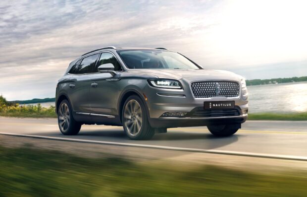 The Lincoln Nautilus SUV is captured in motion on a road near a scenic lake, Lincoln Nautilus Wallpapers, HD Desktop Wallpaper