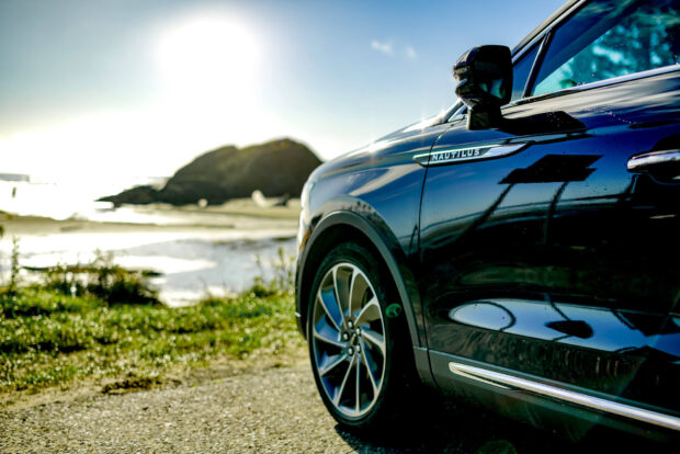 A Lincoln Nautilus is parked near a beach with sunlight reflecting on its surface, HD Desktop Wallpaper