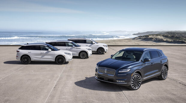 A black Lincoln Nautilus with two white models parked near the ocean shore, 2K Desktop Wallpaper
