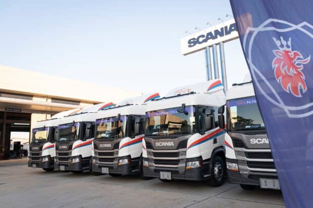 A line of white Scania trucks with blue and red stripes parked near a Scania sign and flag, HD Desktop Wallpaper