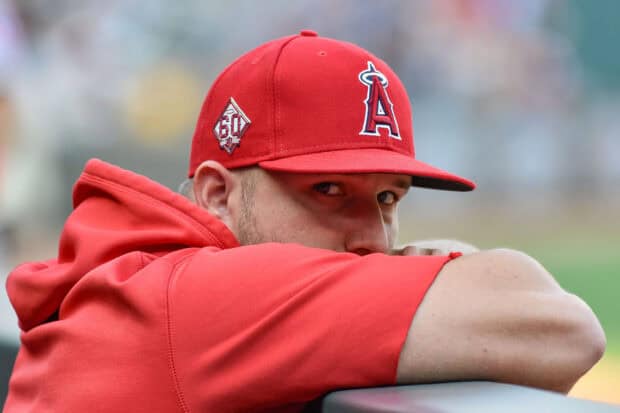 A baseball player from the Los Angeles Angels wearing a red cap and hoodie looks intently while resting his arms, 2K Desktop Wallpaper