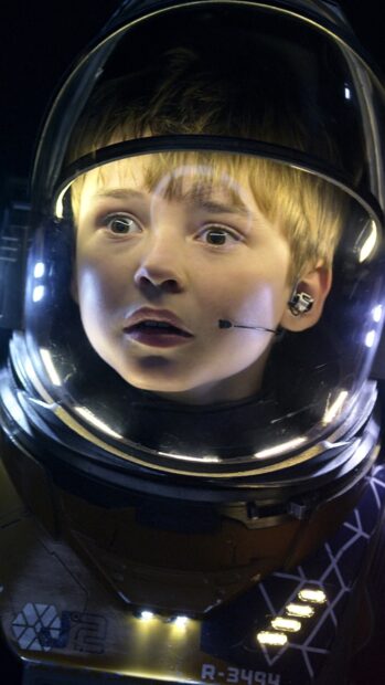 A young astronaut boy looks surprised inside a helmet in Lost In Space Tv Series, 4K Phone Wallpaper