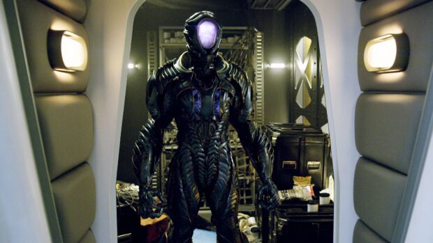 An alien warrior in a detailed suit stands inside a spaceship corridor from Lost In Space TV series, 4K Desktop Wallpaper