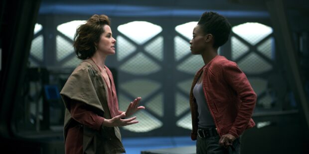 Two Lost In Space characters engage in a serious conversation inside a futuristic corridor, 2K Desktop Wallpaper