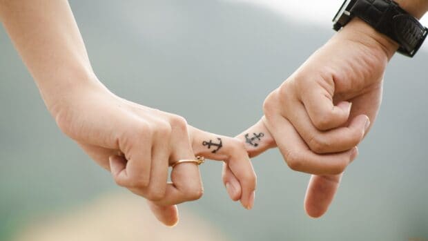 A love couple holds hands showing matching anchor tattoos on their fingers, 4K Desktop Wallpaper
