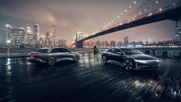 Two Lucid Motors cars are parked on a wet wooden dock with a city skyline and bridge in the background, HD Desktop Wallpaper