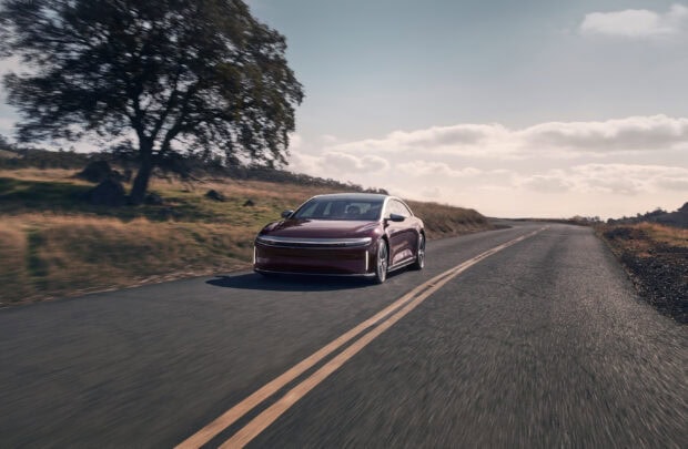 A Lucid Motors drives along a country road under a partly cloudy sky in the afternoon, 2K Desktop Wallpaper
