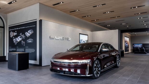 A Lucid Motors electric car is showcased inside a modern showroom with detailed technology panels, HD Desktop Wallpaper