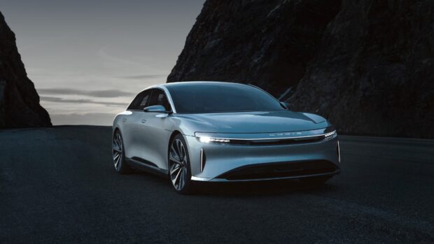 A silver Lucid Motors vehicle is parked on a dark road between tall rocky cliffs during dusk, 4K Desktop Wallpaper