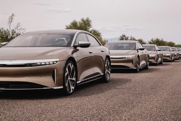 A lineup of Lucid Motors electric sedans is parked on a road under a cloudy sky, HD Desktop Wallpaper