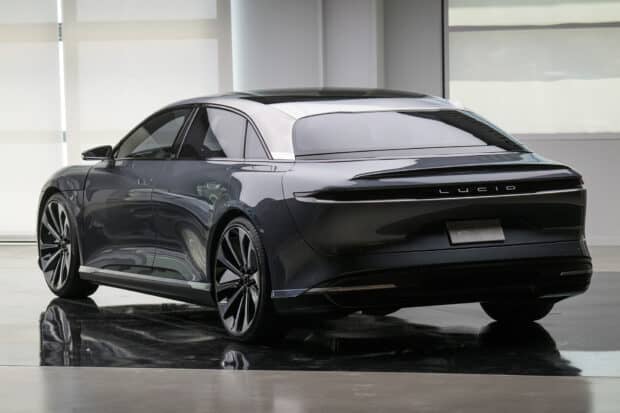 A sleek black Lucid Motors car is displayed indoors reflecting light on the floor, HD Desktop Wallpaper
