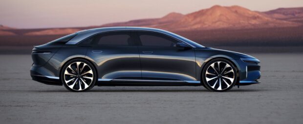 A sleek Lucid Motors electric sedan is parked on a desert flat with mountains in the background, 2K Desktop Wallpaper