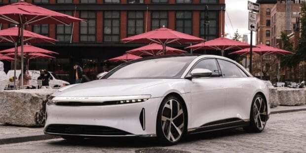 A white Lucid Motors electric car parked on a city street with red umbrellas in the background, HD Desktop Wallpaper
